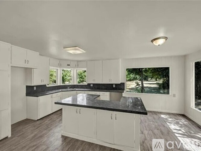 A modern kitchen with white cabinets and a black countertop.