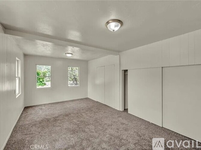 A spacious room with white walls and carpeted floor.