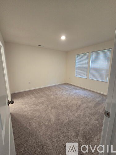 A room with a carpeted floor and a window with blinds.