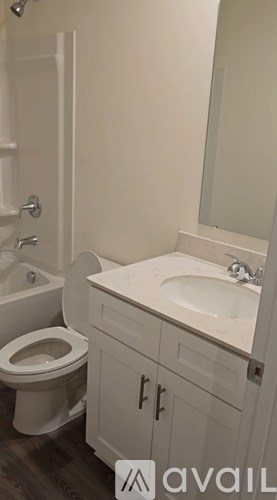A white bathroom with a toilet, sink and mirror.