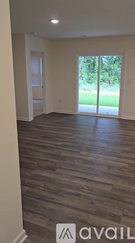 A room with wooden flooring and a sliding glass door leading outside.