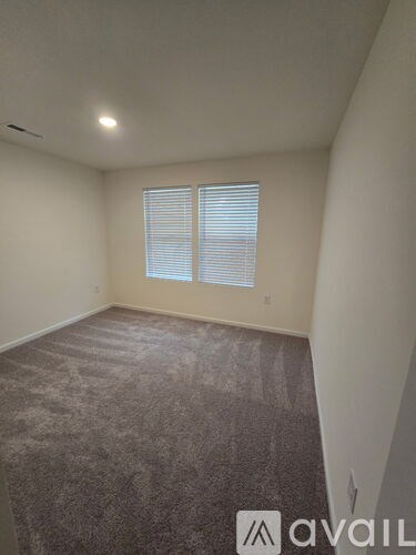 A room with carpeted floor and a window with blinds.