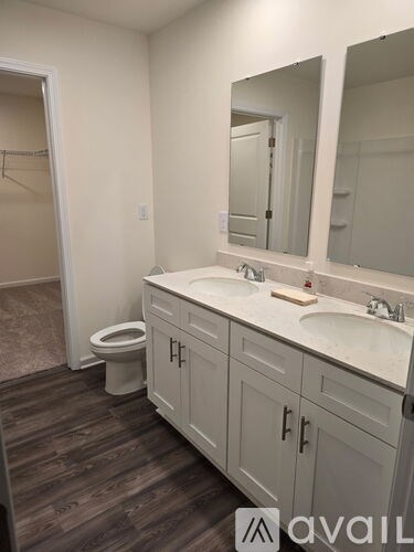 A bathroom with a toilet, sink, and mirror.