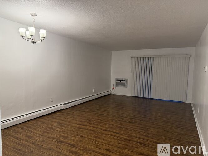 A room with wooden flooring and a chandelier hanging from the ceiling.