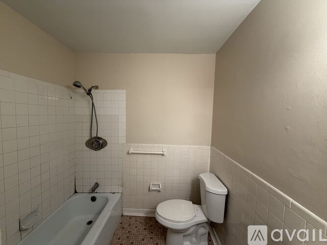 A bathroom with a toilet, a bathtub, and a shower head.