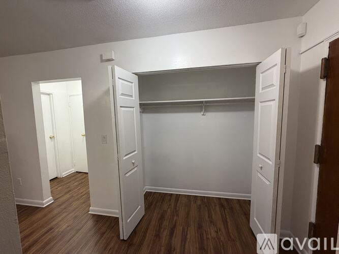 A white closet with a wooden floor and a white door.