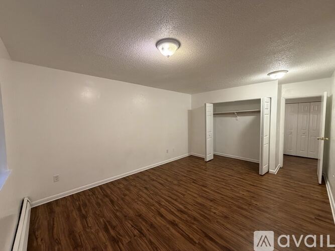 A room with wooden flooring and white walls, with a single light fixture on the ceiling.
