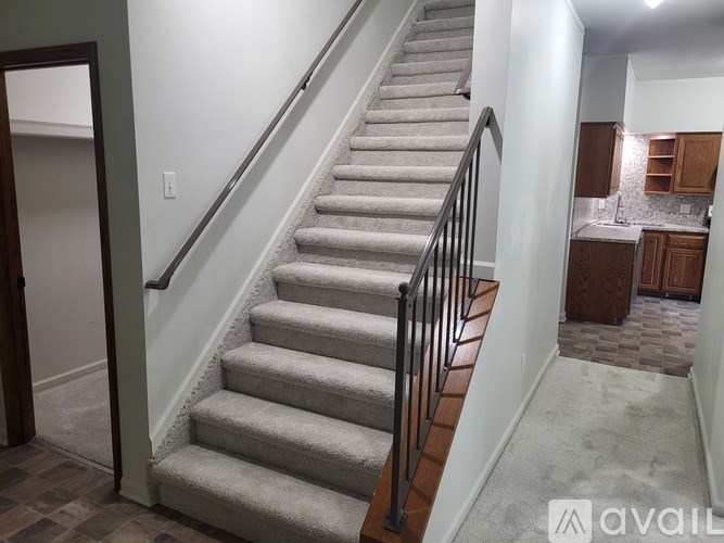 A staircase with a metal railing and a carpeted floor.