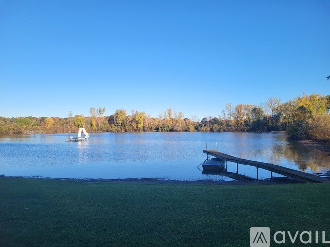 A sailboat is on a lake with a dock in the foreground.
