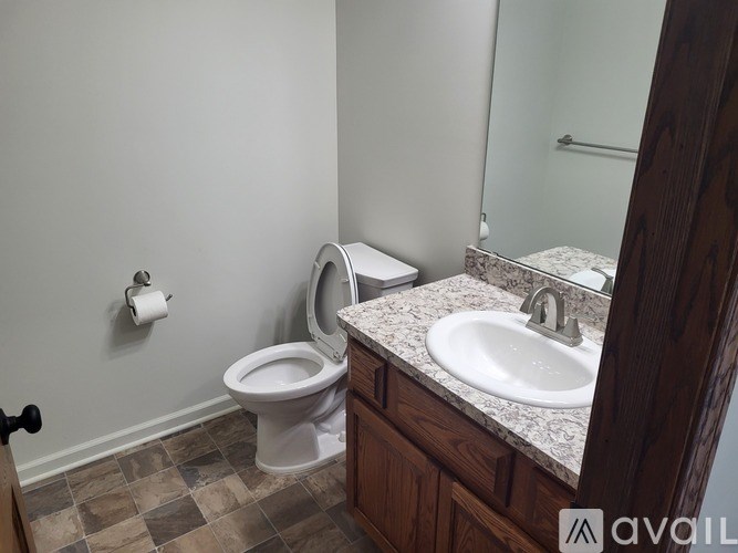 A bathroom with a toilet, sink, and mirror.