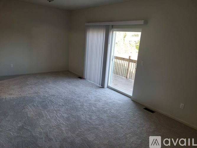 A room with a carpeted floor and sliding glass doors leading to a deck.