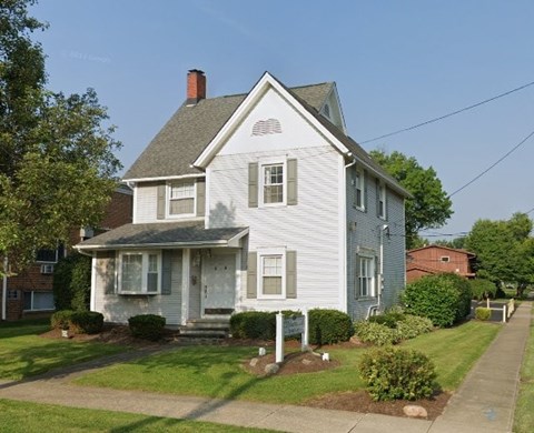 A white house with a grey roof and a small porch.