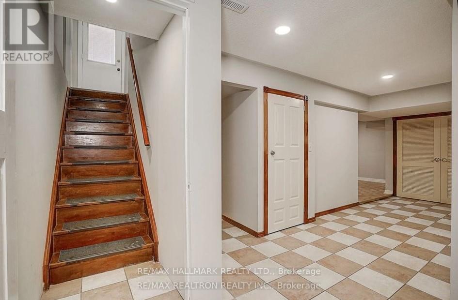 A hallway with a checkered floor and a wooden staircase.