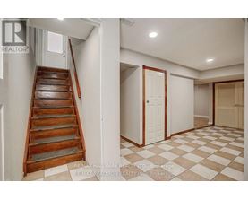 A hallway with a checkered floor and a wooden staircase.