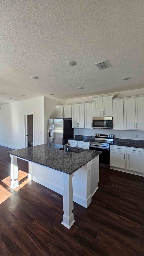 A kitchen with white cabinets and a black countertop.