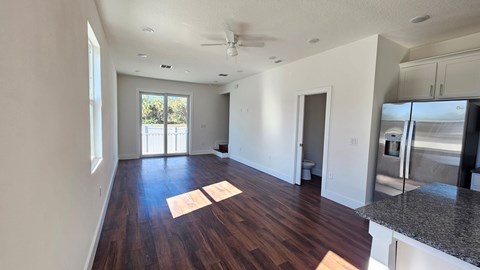 A spacious room with wooden floors and a ceiling fan.