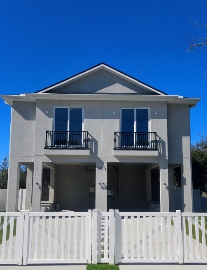 A two-story house with a white fence in front.