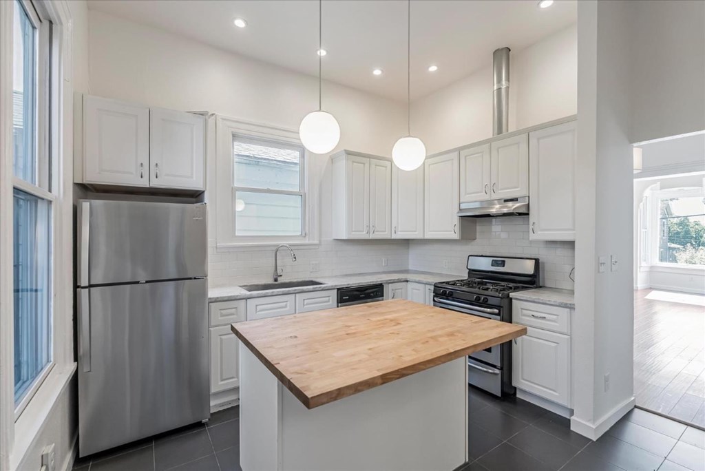 A modern kitchen with a wooden island in the middle.