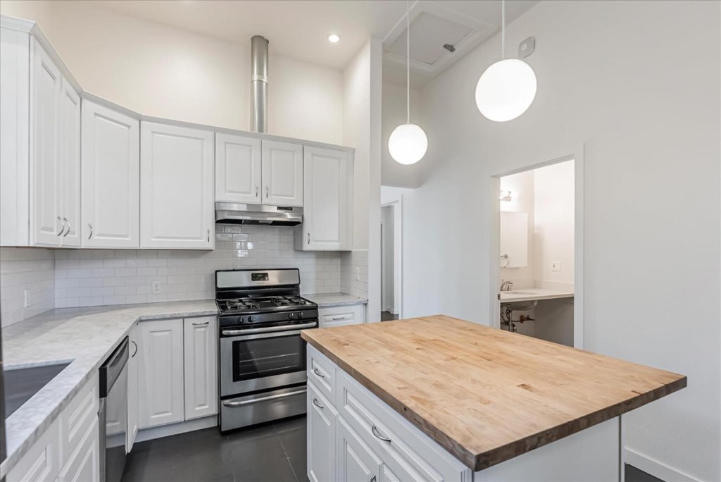 A kitchen with white cabinets and a wooden island.