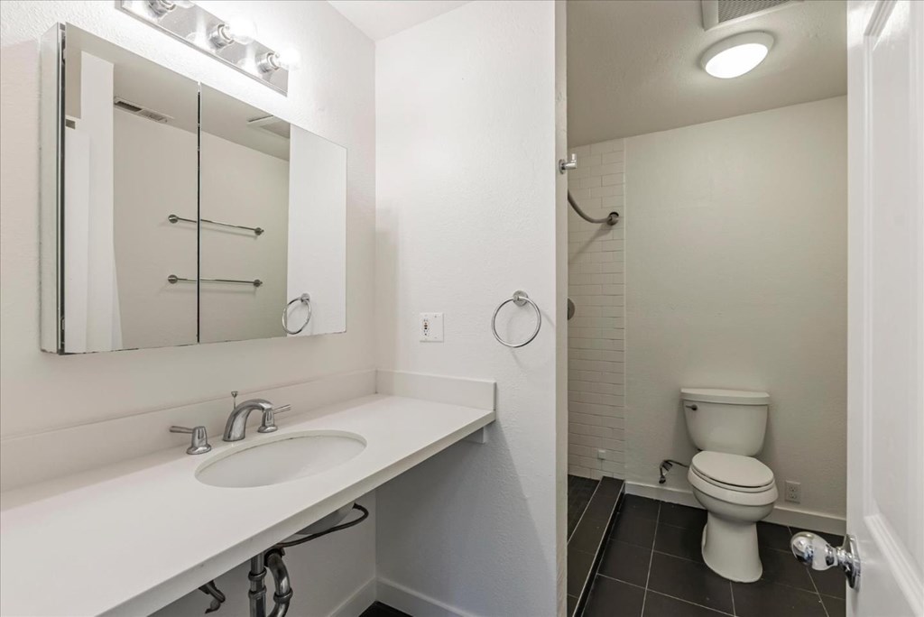 A white bathroom with a toilet, sink, and mirror.