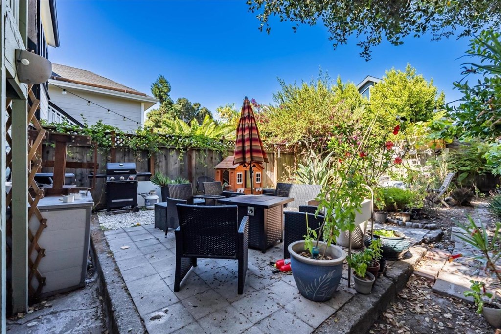 A backyard with a table, chairs, and a small house-like structure.