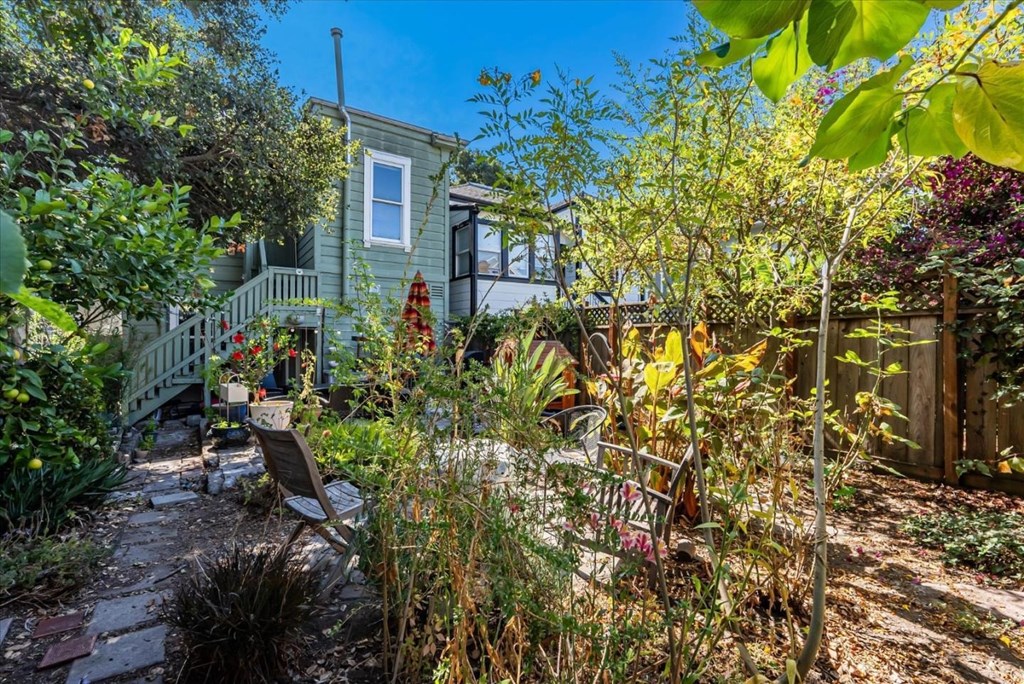 A small house with a green fence and a garden in front.