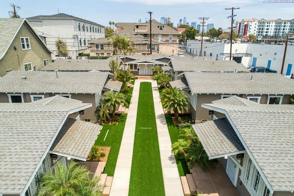 A view of a residential area with houses and a green lawn in the foreground.