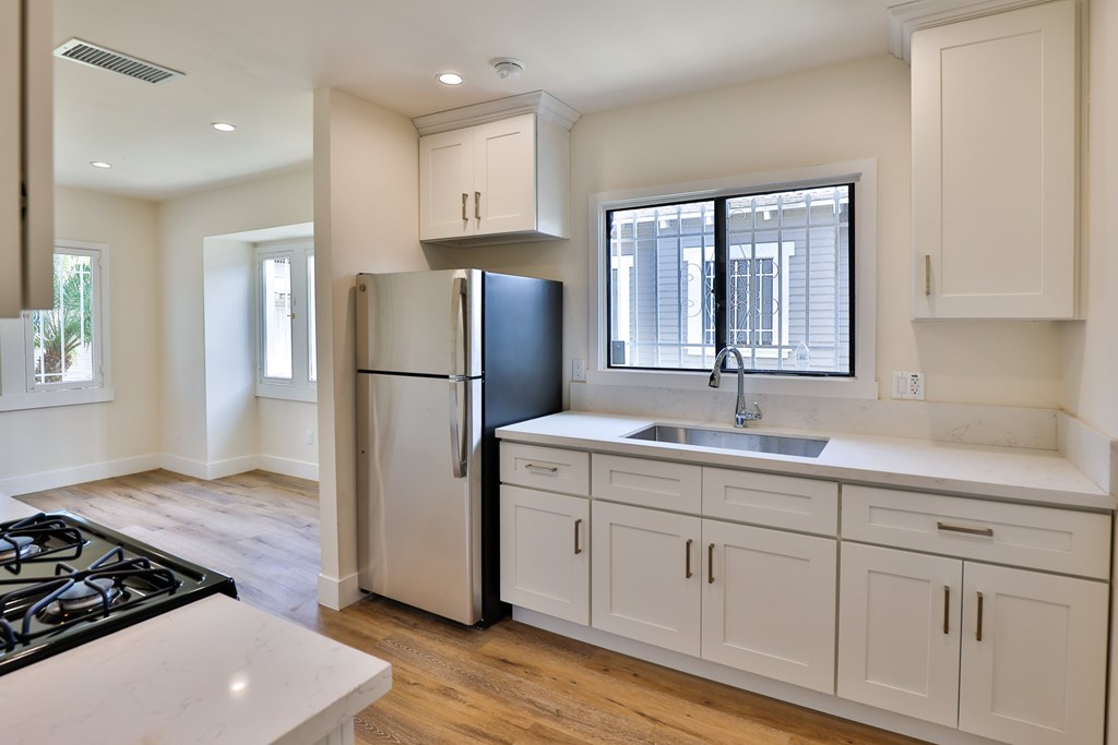 A kitchen with a black stove top and a black refrigerator.