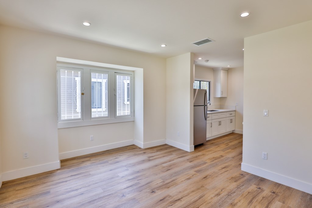 A kitchen with a refrigerator, sink, and cabinets is visible through a window.