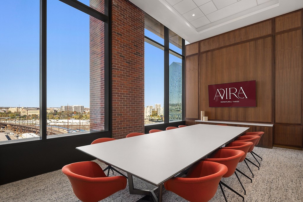 A conference room with a long table and chairs with a view of the city outside the window.