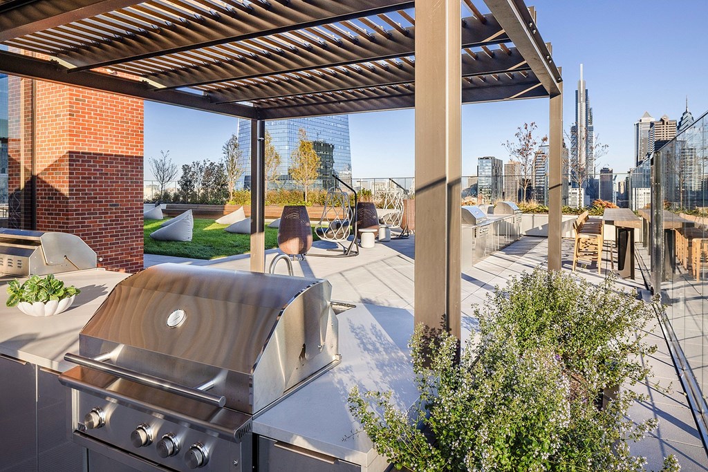 A modern outdoor kitchen with a grill and a view of the city skyline.