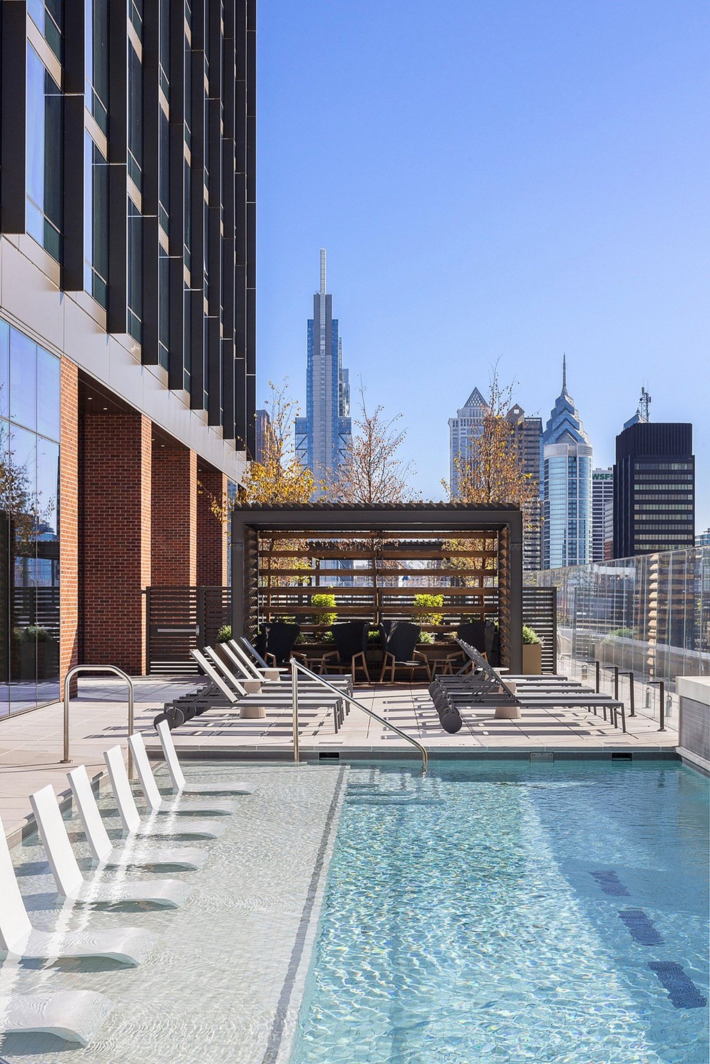 A pool with chairs and a building in the background.