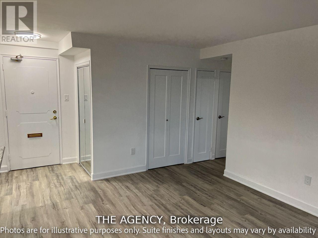 A white door with a brass handle is in a room with white walls and wood flooring.