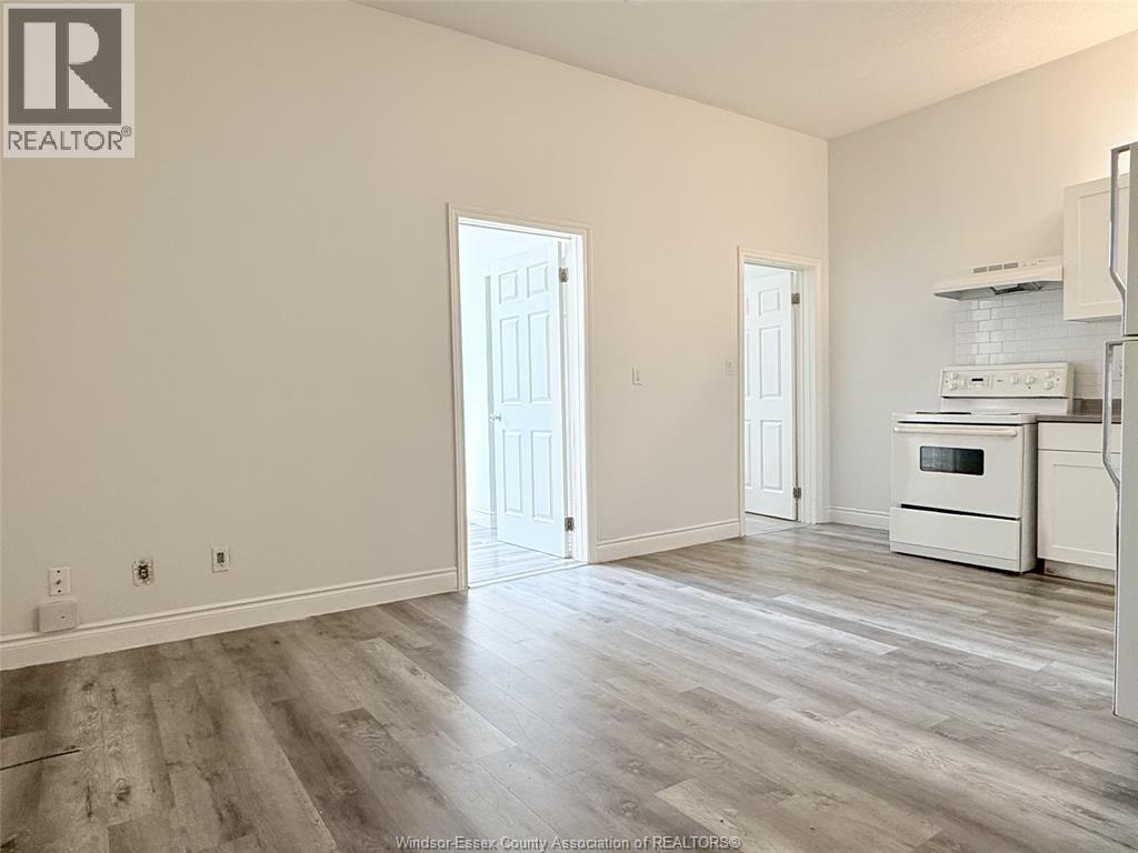 A spacious living room with a kitchen area in the background.