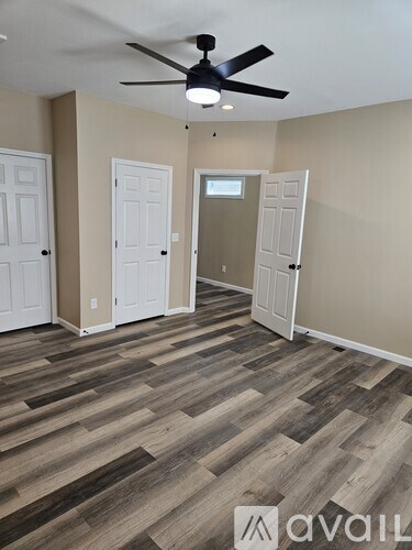 A room with a ceiling fan and wooden flooring.