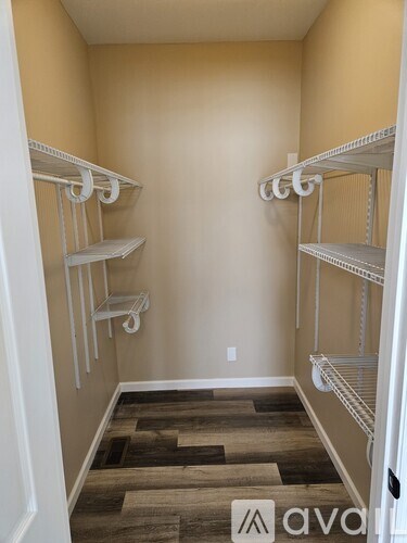 A room with white shelves and wooden flooring.