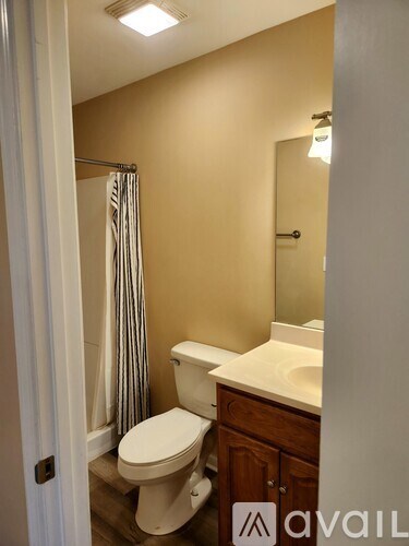 A bathroom with a toilet, sink, and mirror.
