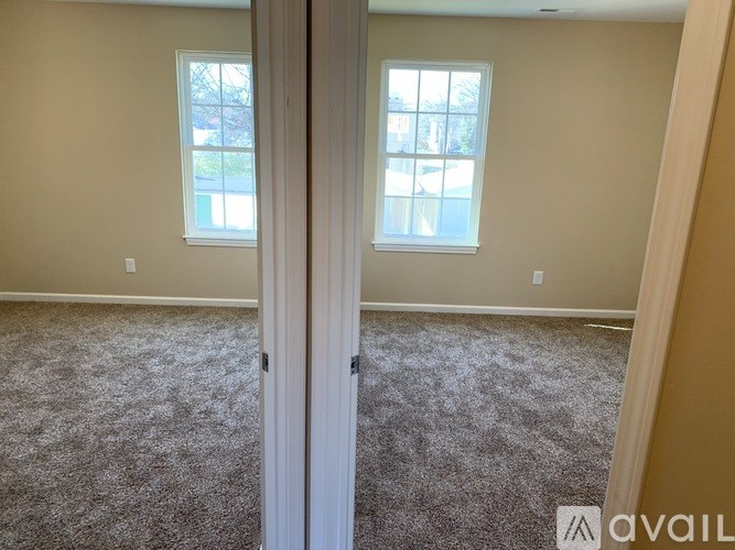A room with a carpeted floor and two windows.