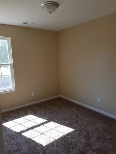 A room with a window and carpeted floor.