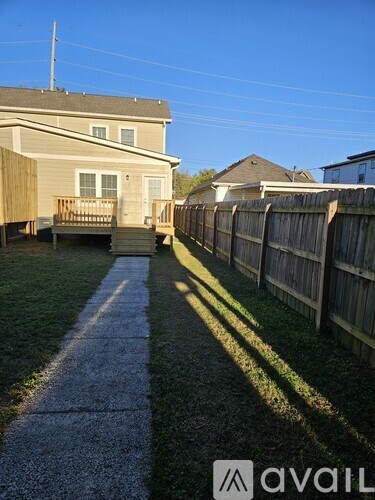 A sunny day in a residential area with houses and a fence.