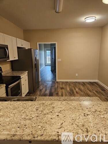 A kitchen with a granite counter top and wooden floors.