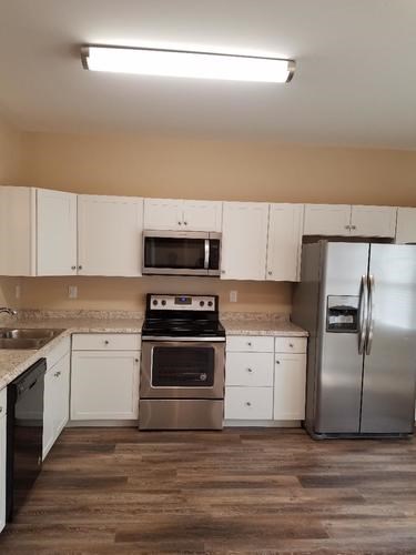 A kitchen with white cabinets and a stainless steel refrigerator.