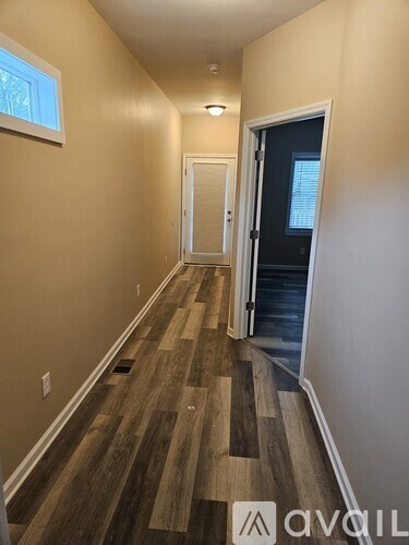 A hallway with wood flooring and a door on the right.