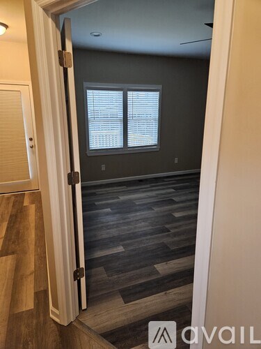 A room with a wooden floor and a window with blinds.
