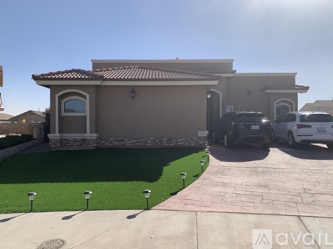 A house with a beige exterior and a brown roof with a car parked in front.