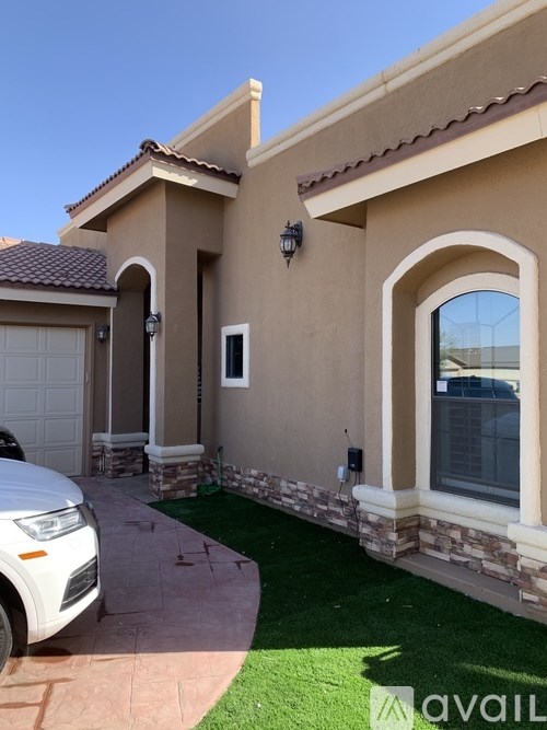 A beige house with a white car parked in front.