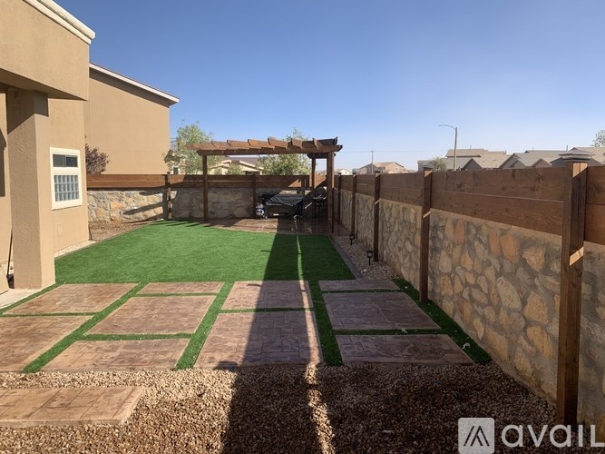 A backyard with a green lawn and a wooden fence.