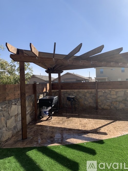 A wooden pergola with a black grill underneath it.