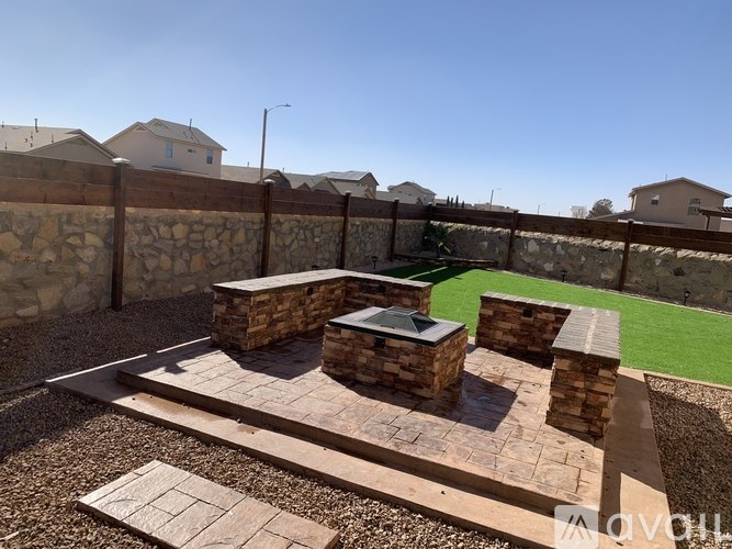A backyard with a stone patio and a stone wall.