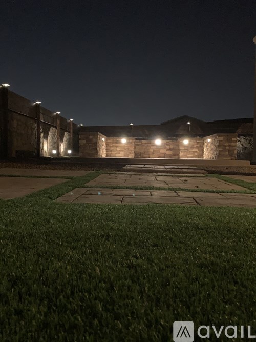 A nighttime view of a well-lit stone wall and pathway.